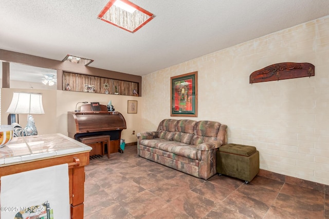 living area with a skylight, a textured ceiling, and baseboards