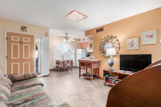 living room featuring visible vents, a ceiling fan, light tile patterned flooring, a textured ceiling, and baseboards