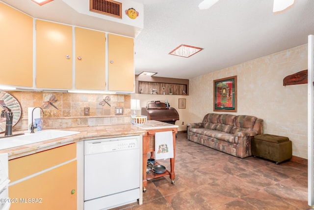 kitchen featuring visible vents, decorative backsplash, white dishwasher, light countertops, and a sink