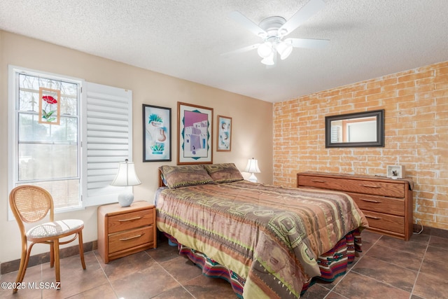 bedroom with a textured ceiling, brick wall, multiple windows, and a ceiling fan