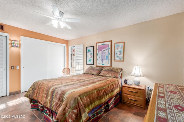 bedroom with a textured ceiling, visible vents, and a ceiling fan