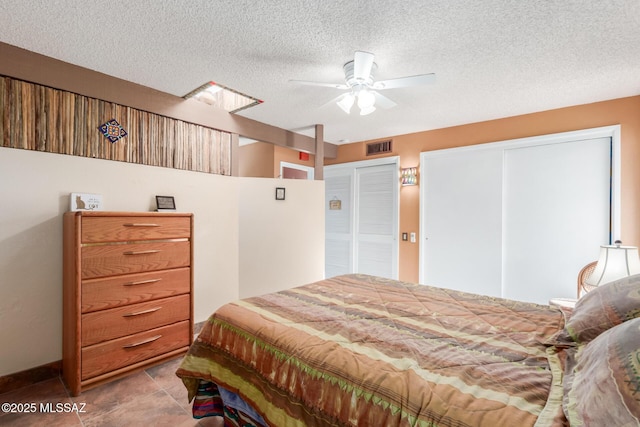 bedroom featuring a textured ceiling, visible vents, and a ceiling fan