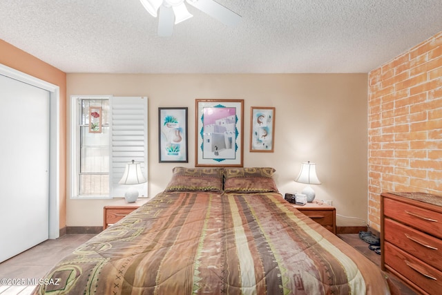 bedroom with ceiling fan, a textured ceiling, baseboards, and light tile patterned floors