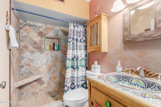 bathroom featuring tiled shower, vanity, and toilet