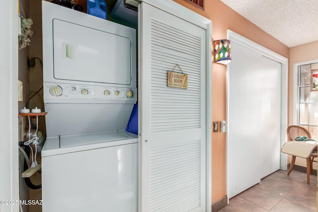 laundry area featuring laundry area, a textured ceiling, stacked washing maching and dryer, and tile patterned floors