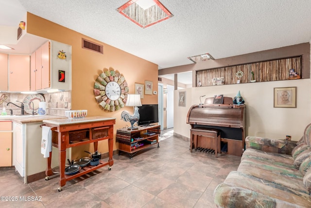 living room featuring visible vents, a textured ceiling, and light tile patterned floors