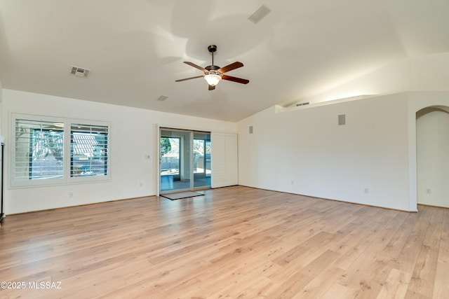 empty room featuring visible vents, arched walkways, lofted ceiling, ceiling fan, and light wood-style floors