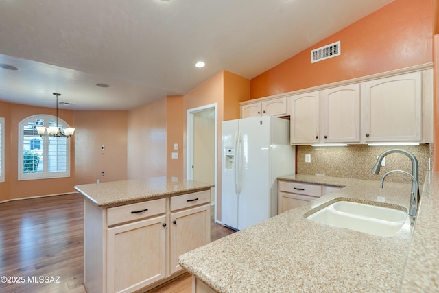 kitchen with a sink, visible vents, vaulted ceiling, a center island, and white fridge with ice dispenser