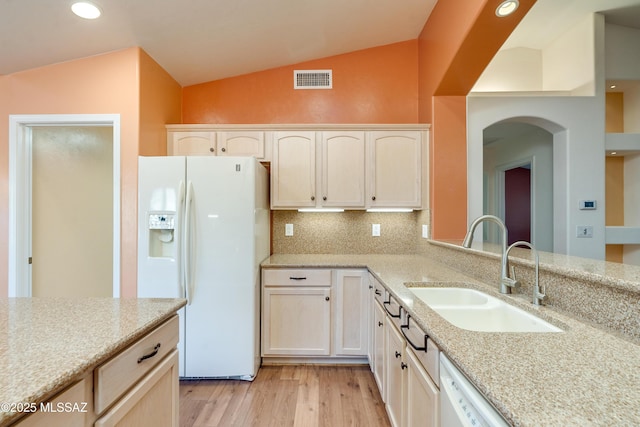 kitchen with lofted ceiling, white appliances, a sink, visible vents, and light stone countertops