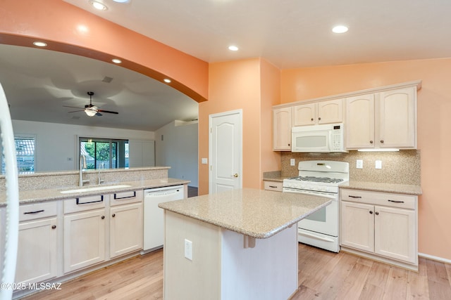 kitchen with white appliances, arched walkways, white cabinets, a ceiling fan, and a center island