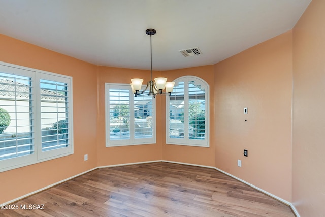 unfurnished dining area featuring light wood-type flooring, an inviting chandelier, baseboards, and visible vents