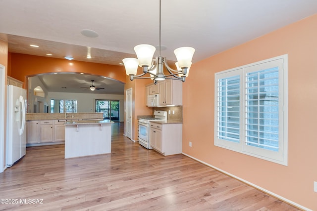 kitchen featuring white appliances, arched walkways, decorative light fixtures, light countertops, and white cabinetry