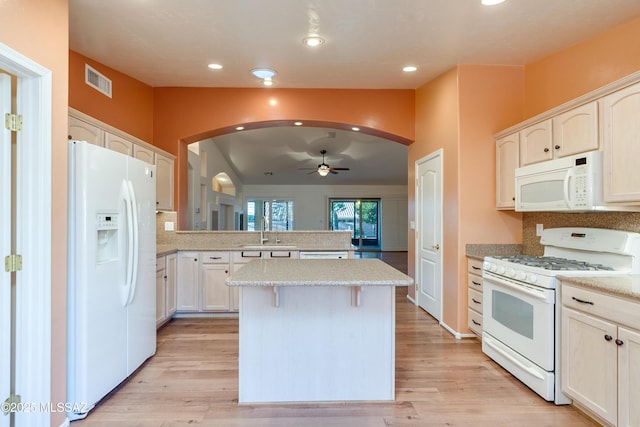 kitchen with arched walkways, white appliances, visible vents, light wood-type flooring, and a center island