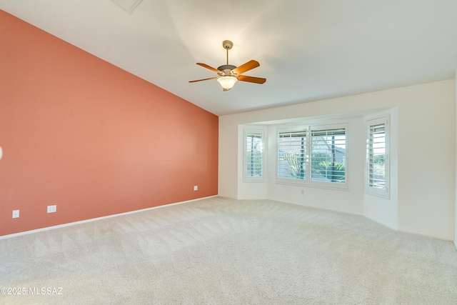 empty room featuring ceiling fan, vaulted ceiling, and light colored carpet