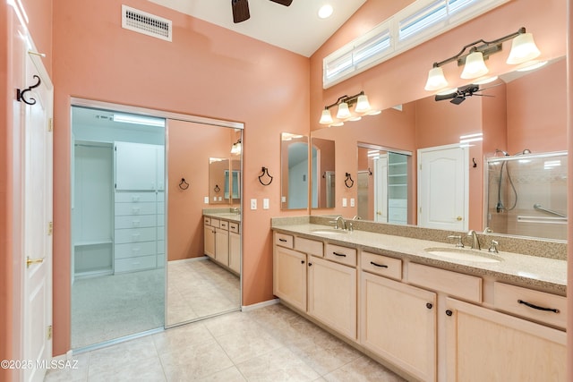 bathroom with a sink, ceiling fan, a walk in closet, and visible vents