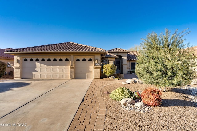 mediterranean / spanish-style house with an attached garage, a tile roof, concrete driveway, and stucco siding