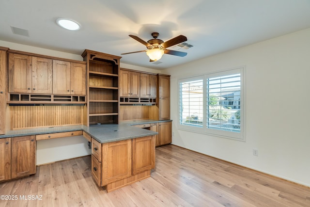 home office with light wood-style floors, ceiling fan, visible vents, and built in study area