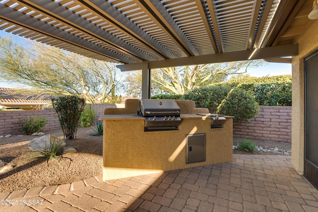 view of patio / terrace featuring a fenced backyard, a pergola, exterior kitchen, and area for grilling