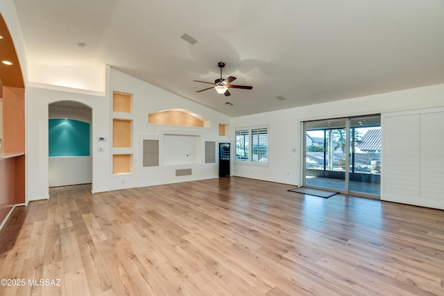 unfurnished living room featuring arched walkways, lofted ceiling, visible vents, ceiling fan, and light wood-type flooring