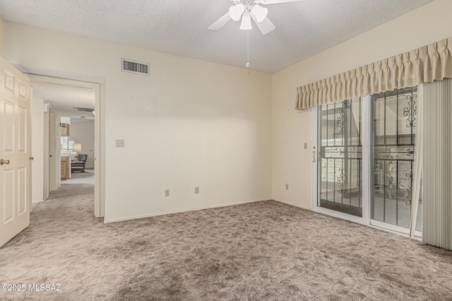 carpeted spare room with visible vents, ceiling fan, a textured ceiling, and baseboards