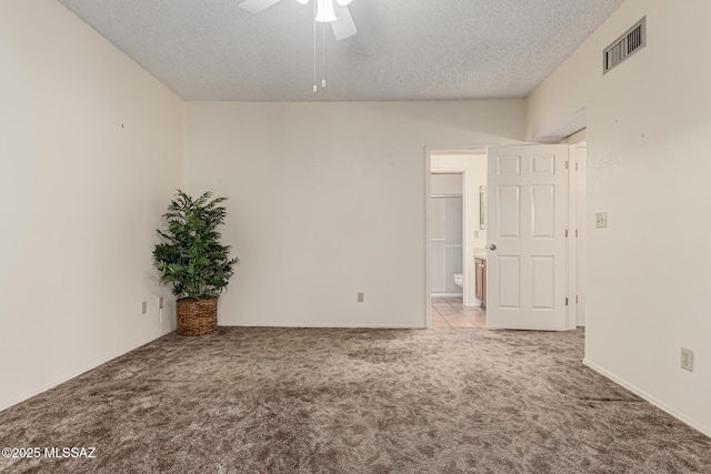 carpeted spare room with ceiling fan, visible vents, and a textured ceiling