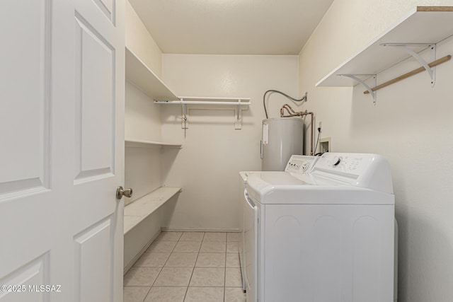 washroom featuring laundry area, light tile patterned floors, washing machine and clothes dryer, and electric water heater