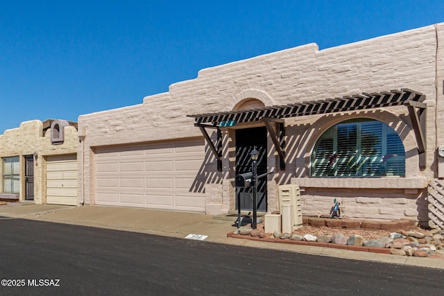 adobe home with a garage and a pergola