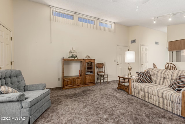 living room featuring lofted ceiling, rail lighting, visible vents, and carpet flooring