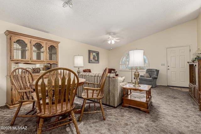 dining room featuring lofted ceiling, a textured ceiling, carpet floors, and a ceiling fan