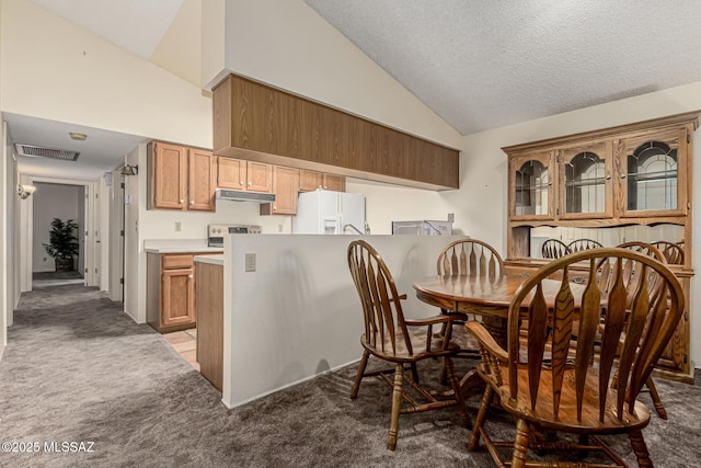 kitchen with high vaulted ceiling, under cabinet range hood, carpet floors, white refrigerator with ice dispenser, and visible vents