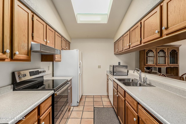 kitchen with under cabinet range hood, appliances with stainless steel finishes, light countertops, and a sink