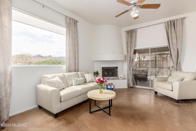 living room featuring a large fireplace, concrete floors, a ceiling fan, and baseboards