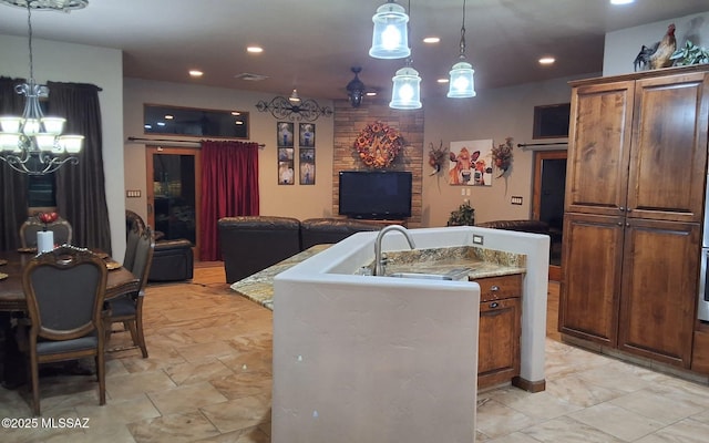 kitchen featuring visible vents, open floor plan, hanging light fixtures, a kitchen island with sink, and light countertops