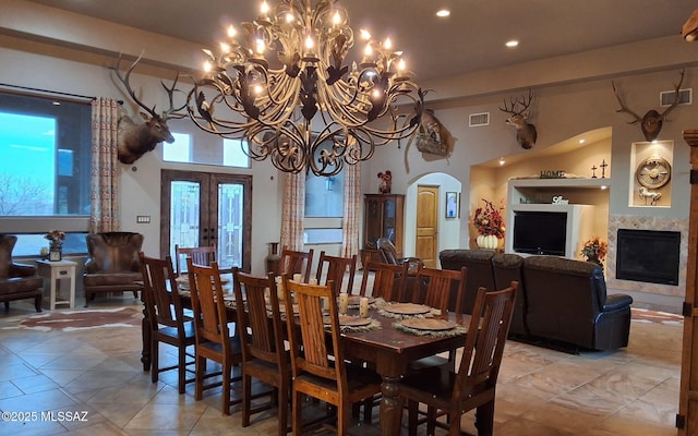 dining room with a premium fireplace, visible vents, arched walkways, and french doors