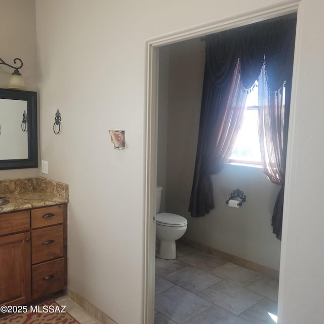 bathroom with toilet, vanity, and baseboards