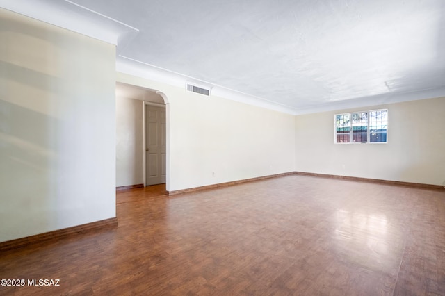 unfurnished room with visible vents, arched walkways, baseboards, and wood finished floors