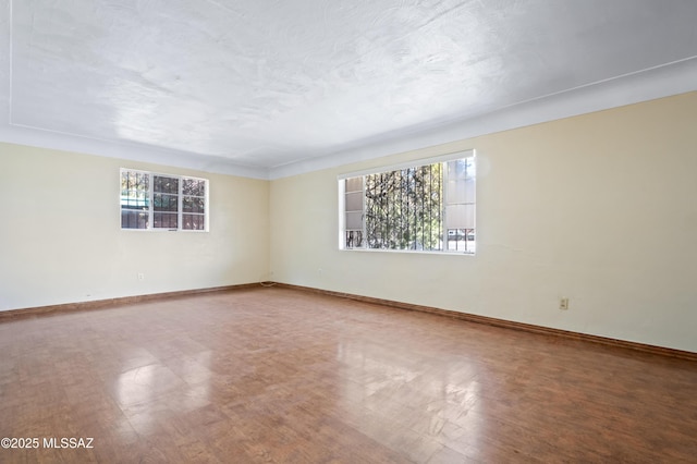 empty room featuring a textured ceiling and baseboards