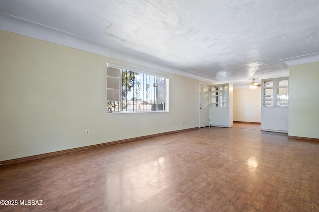 unfurnished living room with a healthy amount of sunlight, baseboards, a ceiling fan, and wood finished floors