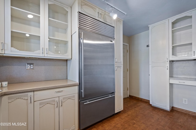 kitchen featuring dark wood-style floors, built in fridge, white cabinetry, light countertops, and glass insert cabinets