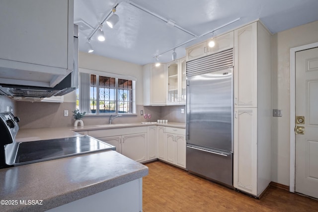 kitchen featuring stainless steel built in refrigerator, electric range, white cabinets, and a sink