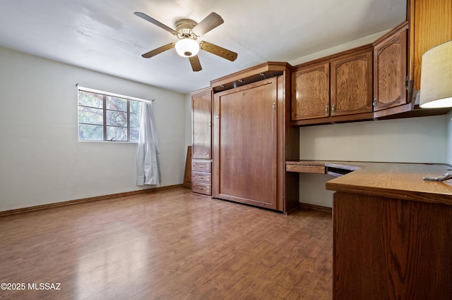 unfurnished bedroom featuring ceiling fan, light wood-style floors, baseboards, and built in study area