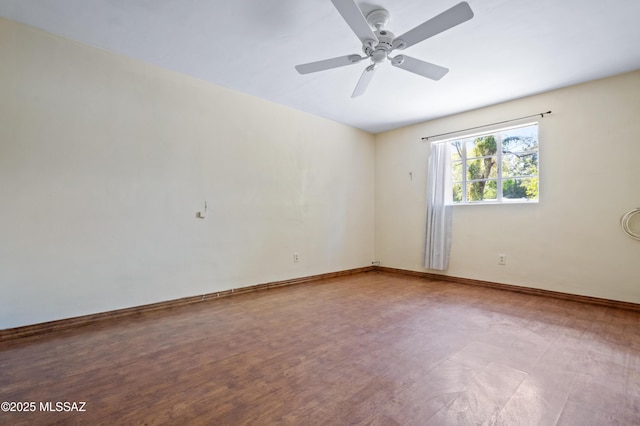 empty room featuring wood finished floors, baseboards, and ceiling fan