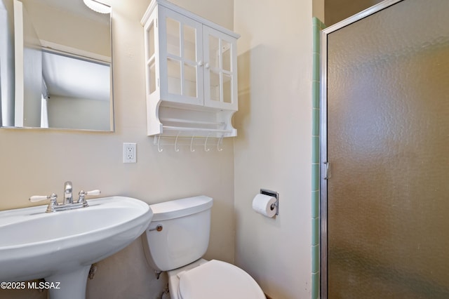 bathroom with a sink, a shower with door, and toilet