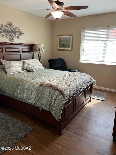 bedroom with wood finished floors, a ceiling fan, and baseboards