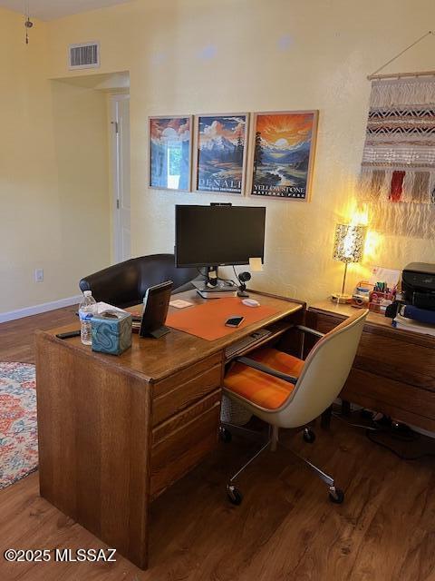 home office with wood finished floors, visible vents, and baseboards