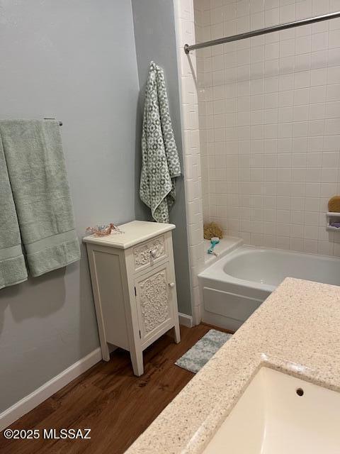 full bath with bathtub / shower combination, baseboards, and wood finished floors