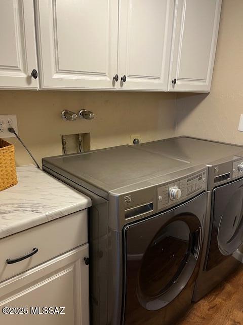 clothes washing area featuring cabinet space, washer and clothes dryer, and wood finished floors