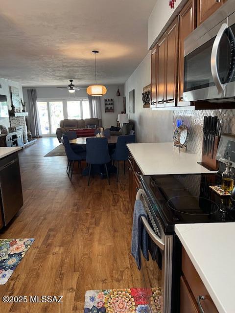 kitchen with open floor plan, light countertops, appliances with stainless steel finishes, and wood finished floors