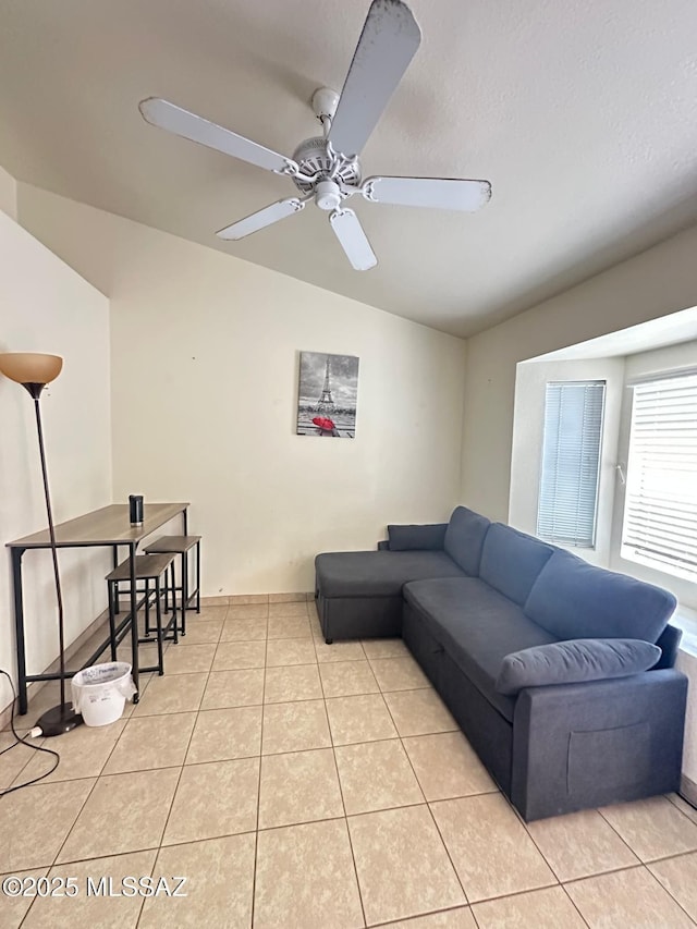 living room with lofted ceiling, ceiling fan, a textured ceiling, and light tile patterned floors