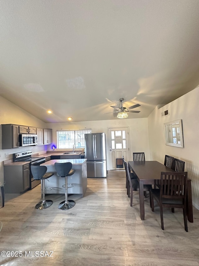 dining area featuring lofted ceiling, light wood finished floors, and visible vents